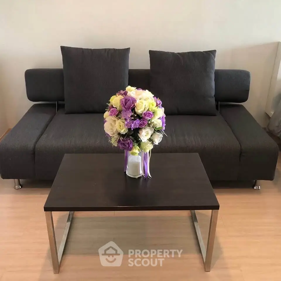 Modern living room with sleek sofa and elegant floral centerpiece on coffee table.