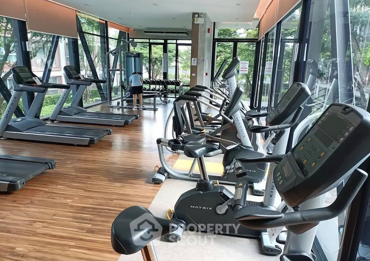 Modern gym with state-of-the-art equipment and large windows offering a lush garden view.