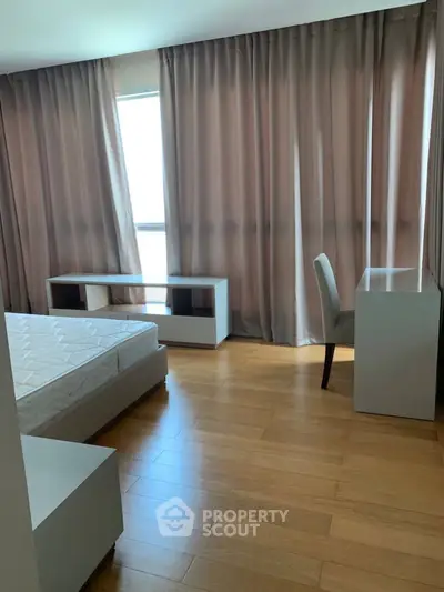 Spacious bedroom with wooden flooring and large windows for natural light.