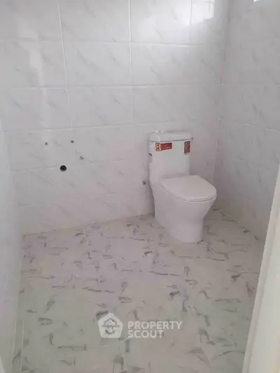 Modern bathroom with sleek white tiles and a new toilet fixture.
