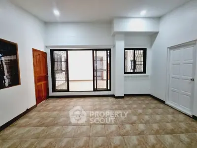 Spacious empty room with tiled flooring and large windows for natural light.