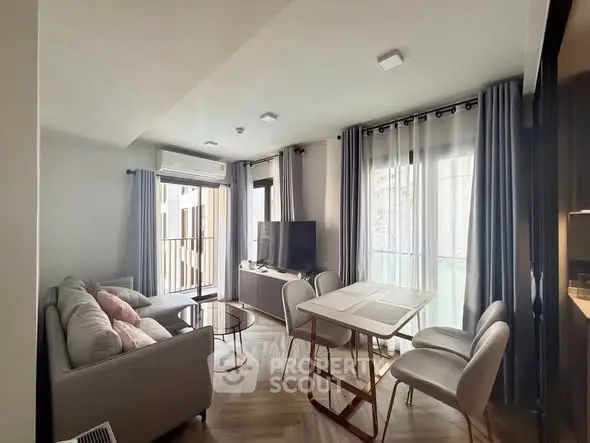 Modern living room with balcony access, featuring stylish furniture and natural light.