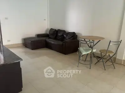 Spacious living room with leather sofa and dining set, perfect for cozy gatherings.