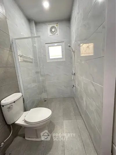 Modern minimalist bathroom with sleek tiles and glass shower enclosure.