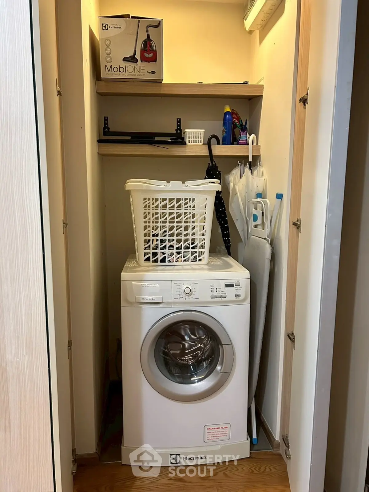 Compact laundry area with washing machine and storage shelves in modern home.