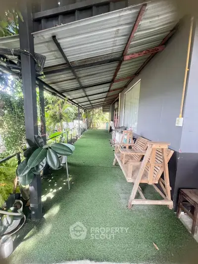 Charming outdoor corridor with lush greenery and cozy seating area, perfect for relaxation.