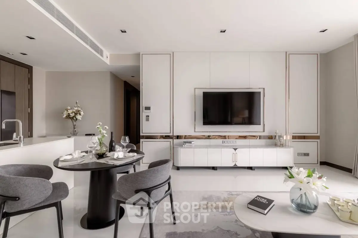 Modern living room with sleek furniture and elegant decor, featuring a large TV and open layout.