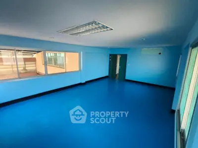 Spacious blue-painted room with large windows and bright lighting, ideal for office or studio space.