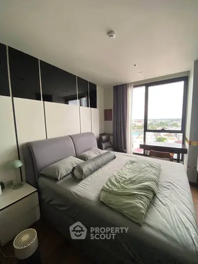 Spacious bedroom with large window offering a stunning city view, modern decor, and cozy bedding.