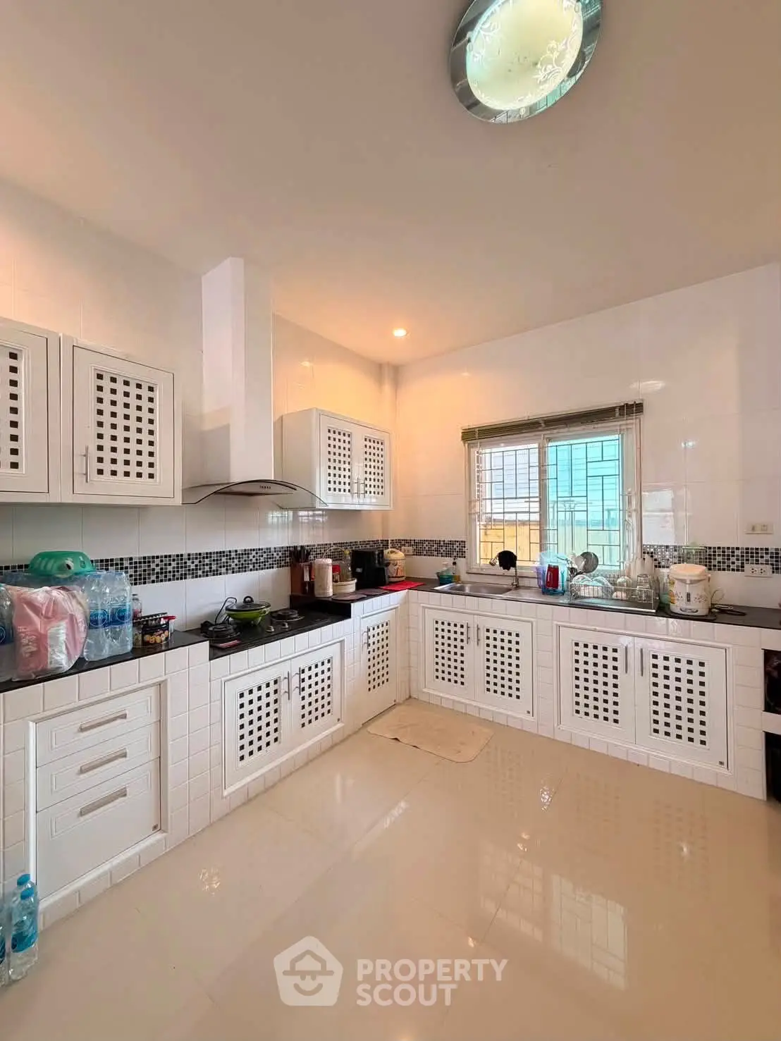 Spacious modern kitchen with sleek white cabinetry and black countertops, perfect for culinary enthusiasts.