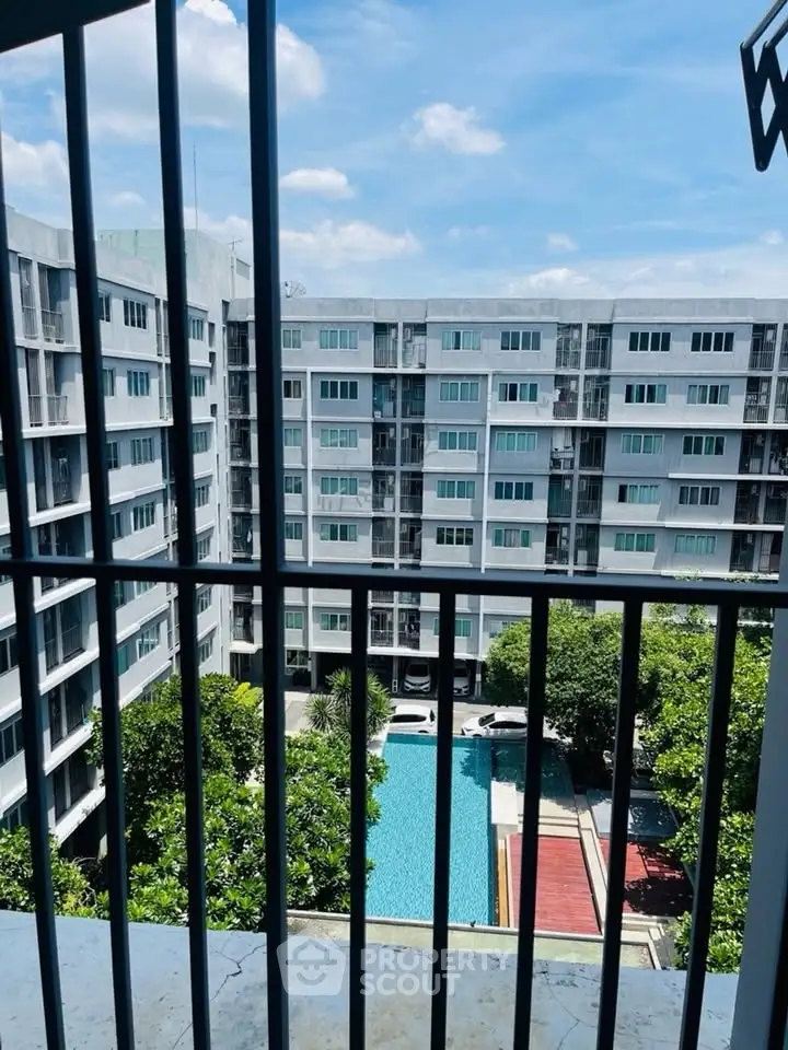 Modern apartment complex with pool view from balcony, showcasing urban living and leisure amenities.