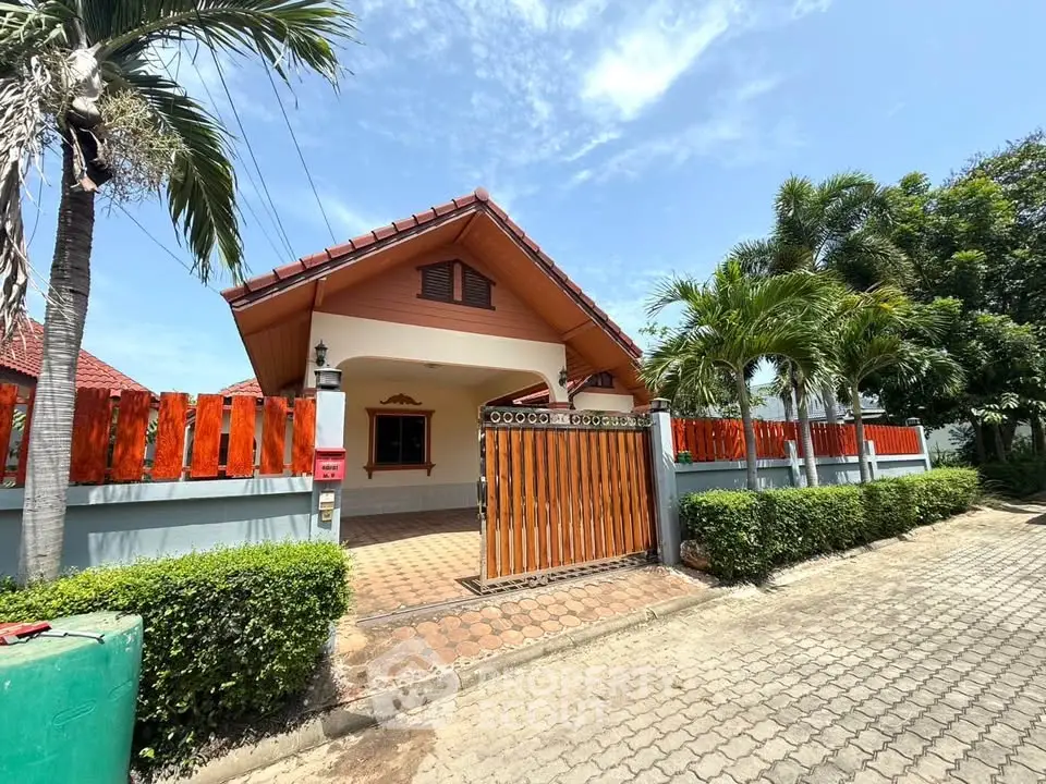 Charming single-story house with red roof and lush greenery in a serene neighborhood.