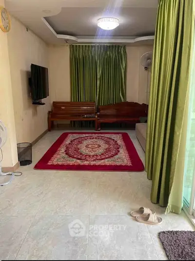 Cozy living room with elegant green curtains and wall-mounted TV, featuring a stylish red carpet and wooden seating.