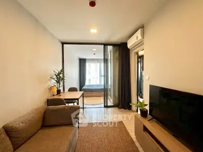 Modern living room with cozy sofa, TV, and dining area leading to a bedroom.