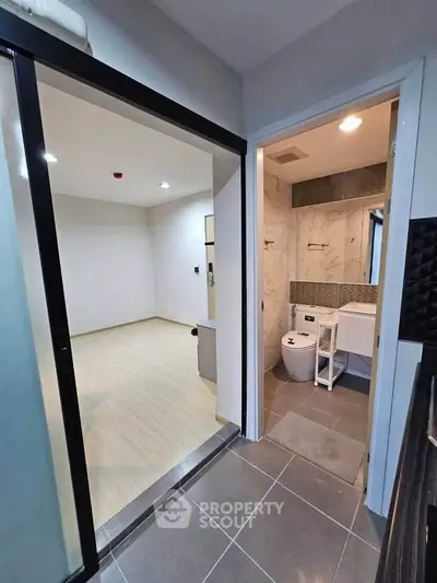 Modern apartment interior with sleek bathroom and open living space, featuring contemporary design and neutral tones.