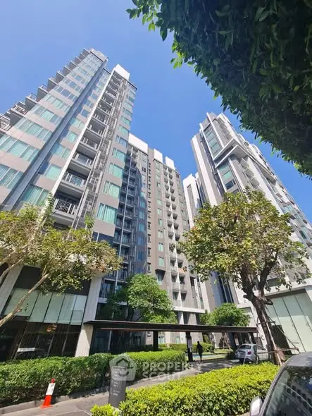 Modern high-rise residential building with lush greenery and clear blue sky.