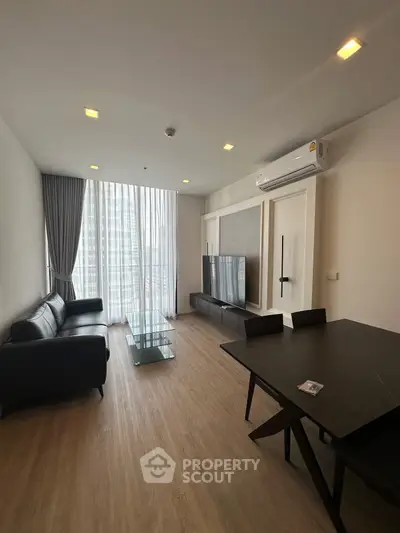 Modern living room with sleek furniture and large windows offering city views.