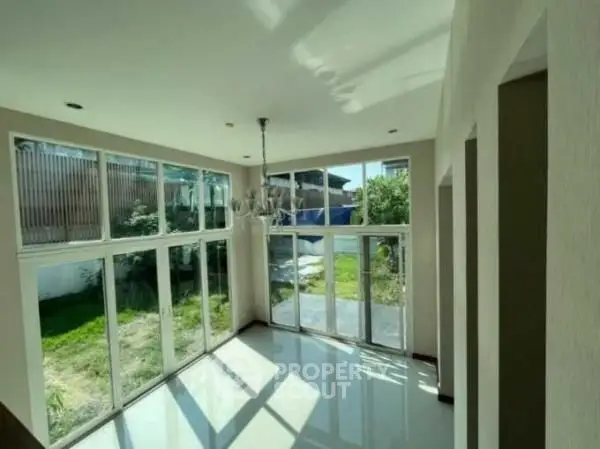 Spacious sunlit room with large windows and garden view