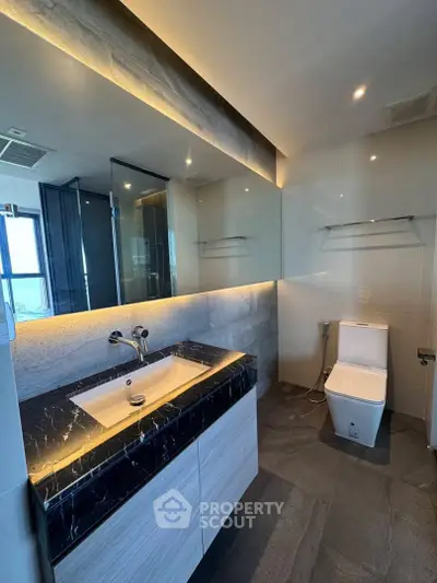 Luxurious modern bathroom with sleek black marble countertop and elegant lighting.