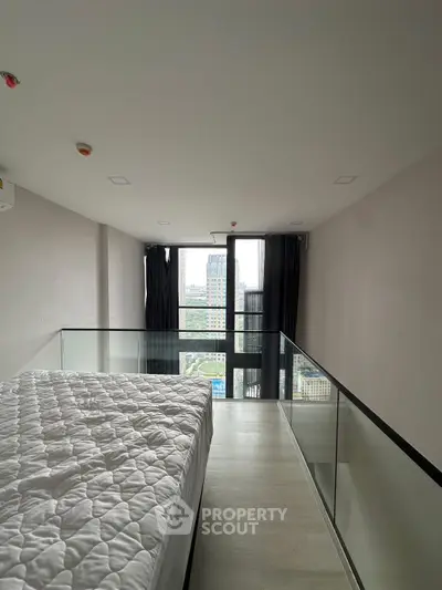 Modern bedroom with city view and glass railing in high-rise apartment
