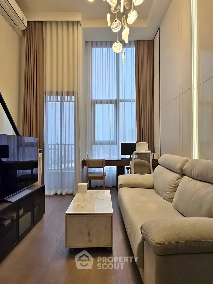 Modern living room with high ceilings, elegant chandelier, and cozy sofa in a stylish apartment.