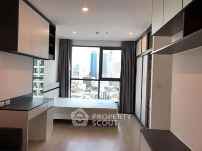 Modern bedroom with city view and sleek built-in storage in high-rise apartment.