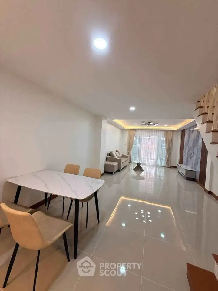 Spacious modern living room with elegant marble dining table and cozy seating area.