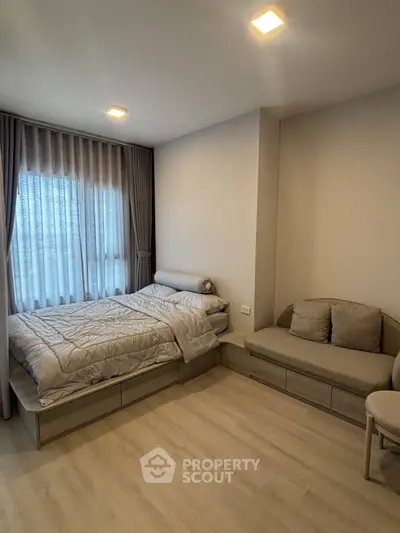 Cozy bedroom with modern decor and natural light, featuring a comfortable bed and stylish seating area.