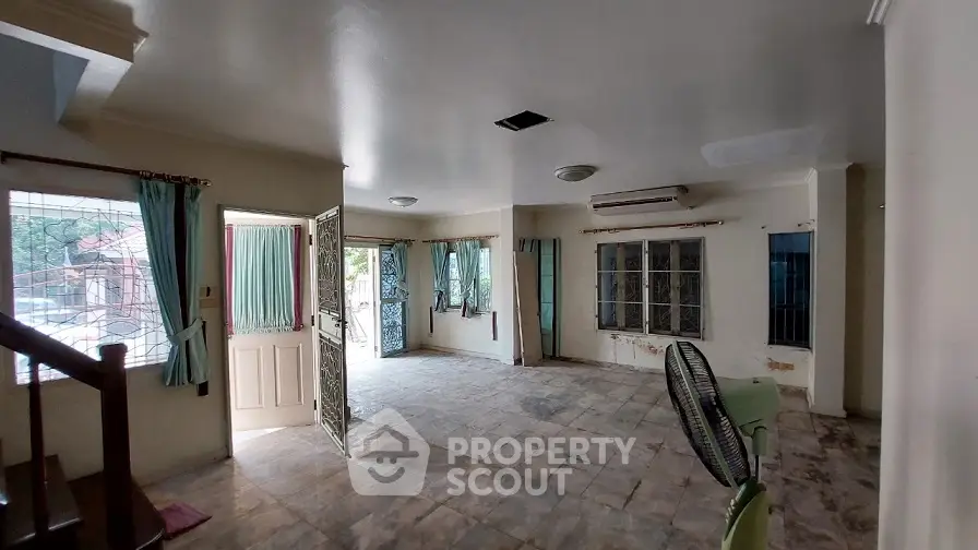 Spacious living room with open door and large windows, ideal for natural light.