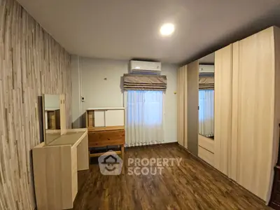 Spacious bedroom with wooden flooring and modern furniture