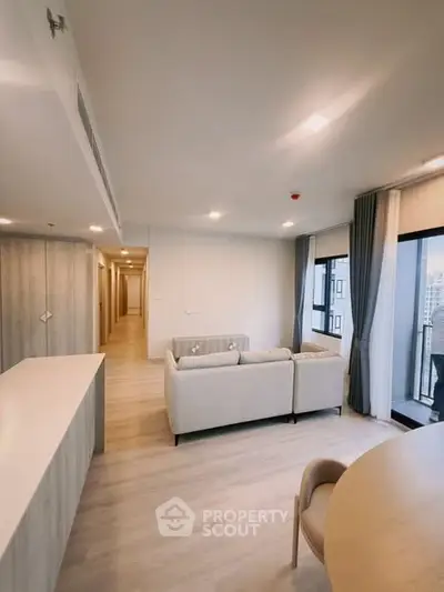 Spacious modern living room with large windows and balcony access in a high-rise apartment.
