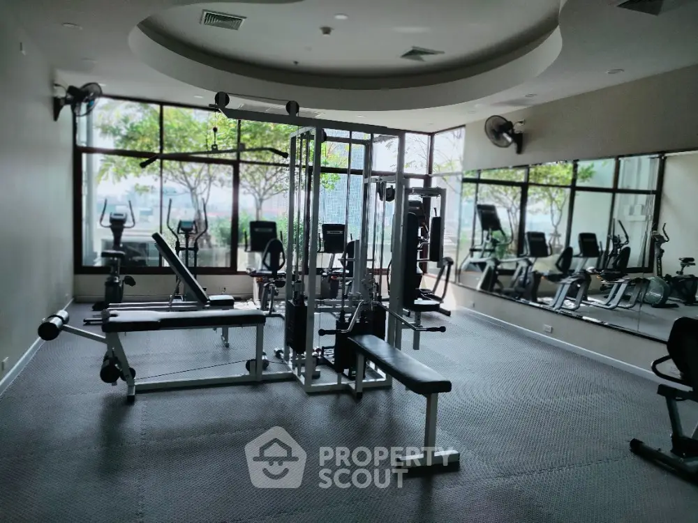 Spacious gym with modern equipment and large windows offering a scenic view.