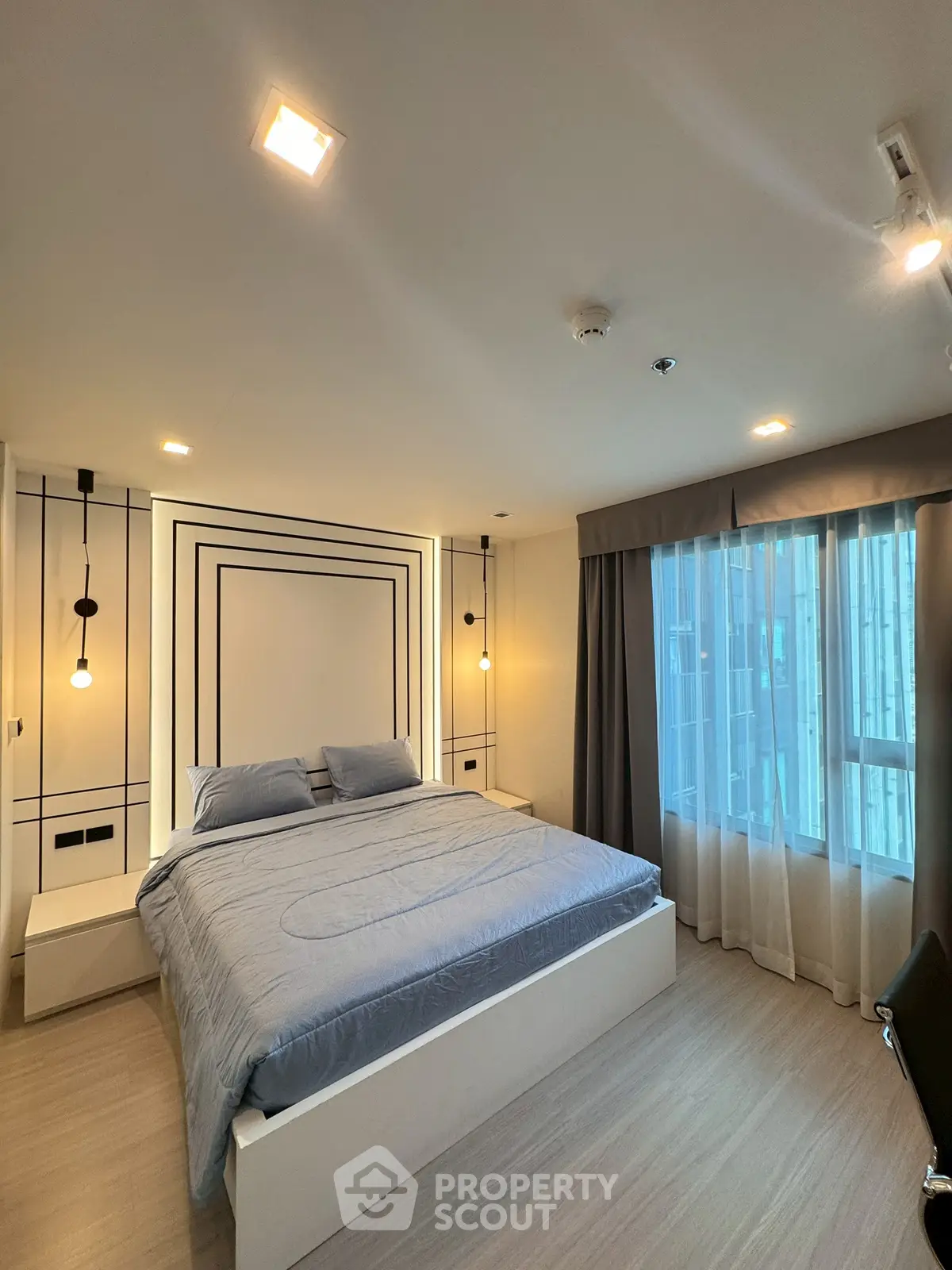 Modern bedroom with stylish decor and large window offering natural light.