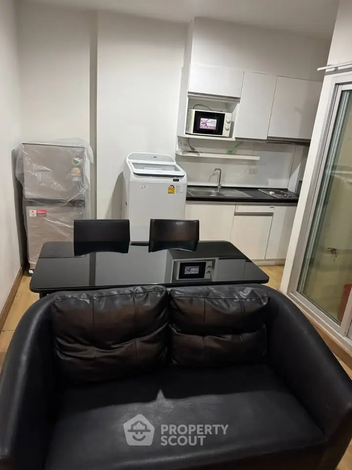Modern compact kitchen with washing machine and microwave in cozy apartment