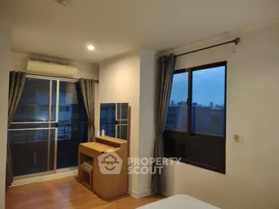 Spacious bedroom with balcony and city view, featuring modern furniture and ample natural light.