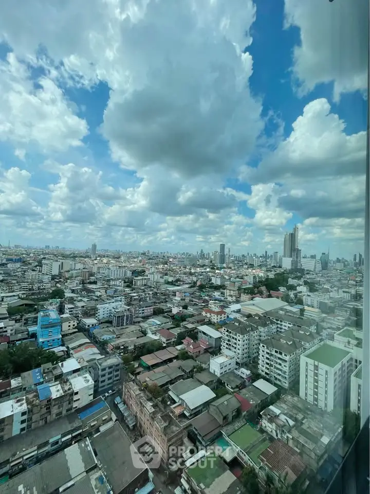 Stunning cityscape view from high-rise building with expansive skyline and clouds.