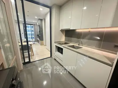Modern kitchen with sleek cabinetry and open layout leading to a bright living room.