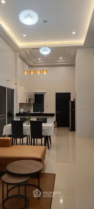 Modern open-plan living and dining area with high ceilings and elegant lighting.
