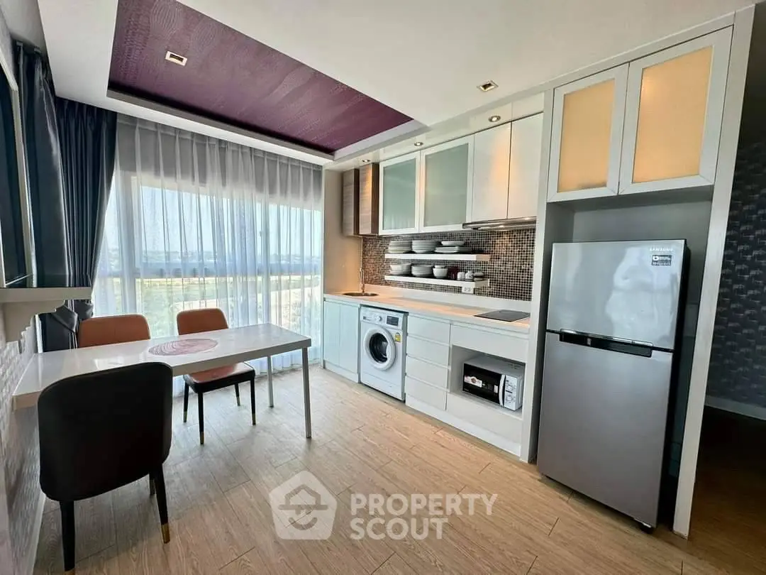 Modern kitchen with dining area, featuring sleek appliances and large windows for natural light.