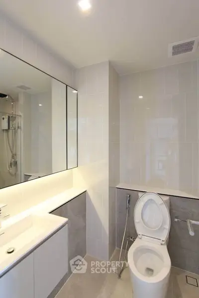 Modern bathroom with sleek fixtures and large mirror in contemporary apartment.
