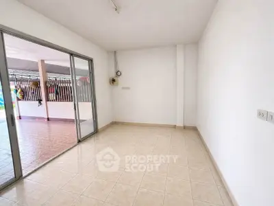 Spacious empty room with tiled floor and sliding glass doors leading to a covered patio.