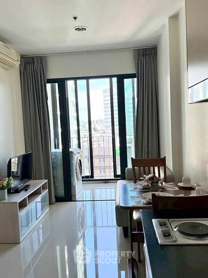 Modern living room with balcony view, featuring sleek furniture and a washing machine.