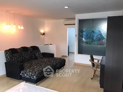 Spacious living room with modern decor and stylish lighting, featuring a comfortable sofa and work desk.