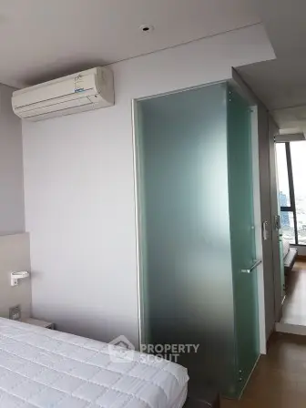Modern bedroom with air conditioning and frosted glass door, offering a sleek and comfortable living space.