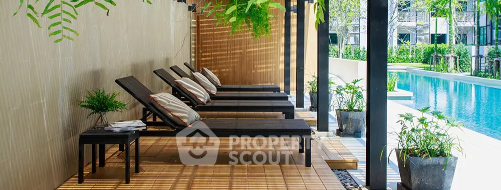 Luxurious poolside area with stylish lounge chairs and lush greenery, perfect for relaxation and leisure.