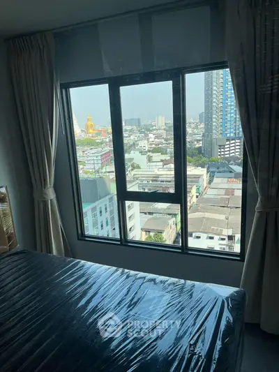 High-rise bedroom with city view through large window, featuring modern curtains and natural light.