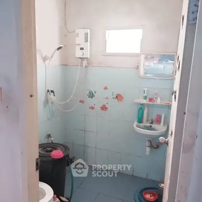 Cozy bathroom with shower and wall-mounted water heater, featuring playful fish-themed tiles.