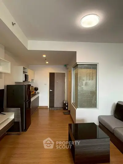 Modern living room with open kitchen, sleek furniture, and wooden flooring in a stylish apartment.