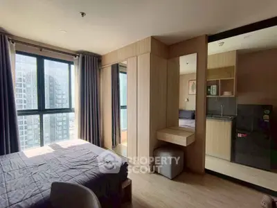 Modern bedroom with large window and stylish kitchen area in urban apartment