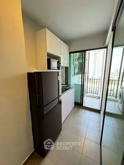 Modern kitchen with sleek appliances and balcony view in urban apartment